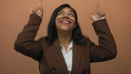 African american woman raising index fingers upward with broad smile in studio; optimism motivation...