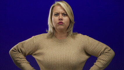 Woman pointing finger in studio setting wearing beige sweater with intense gaze and furrowed brow;...