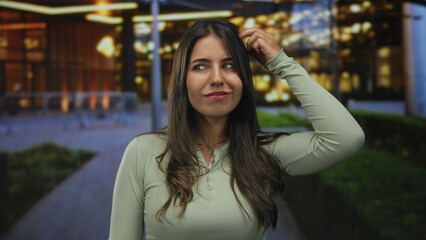 Woman on street posing at night in urban setting, exuding confidence and energy with vibrant surroundings conveying a lively city atmosphere outdoors.