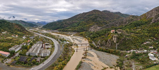 Aerial panorama of Rubik’s winding river, roads and scattered homes, with the hilltop monastery set against rugged autumn mountains.