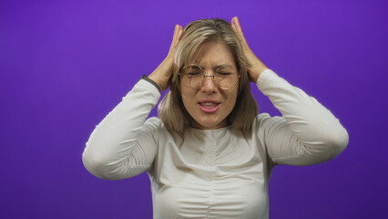 Fototapeta premium Woman shouting with raised hands in purple studio wearing white shirt and round glasses; frustration exhaustion stress.