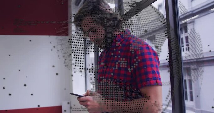 Man looking down at phone, checking tech messages while dotted globe decal overlaying view