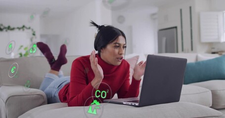 Woman lying on sofa using laptop, tapping screen, researching energy icons covering hands