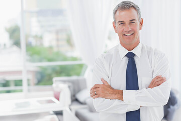 Middle-aged man standing on right in modern living room, wearing tie and wedding ring, copy space