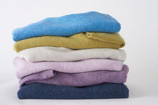 Stack of colorful cashmere sweaters folded neatly on white background