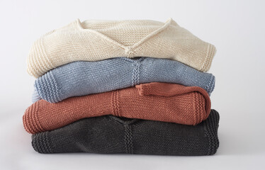 Stack of knitted baby cardigans in soft natural colors for newborn