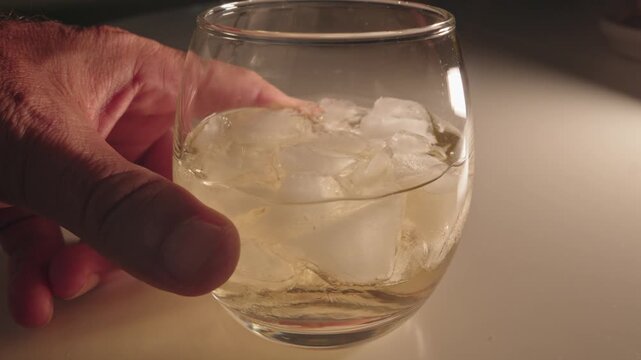 Swirling a Refreshing Iced White Wine Glass at Night