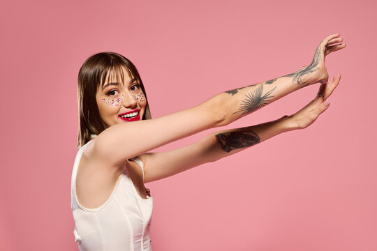 Charming young woman in trendy outfit poses joyfully against a pink backdrop