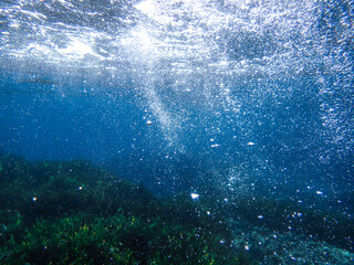 Ocean underwater rays of light background, under blue water sunlight. Underwater background, ocean or sea surface seen from under water. Rays of light beams, abstract marine backdrop. Nature landscape