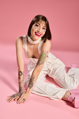 Fashionable young woman radiating joy in a stylish pink setting with vibrant tattoos