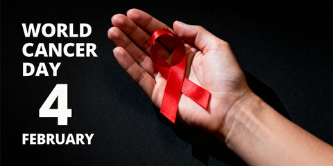 World cancer day 4 february text on black background with hand holding red ribbon, promoting cancer awareness