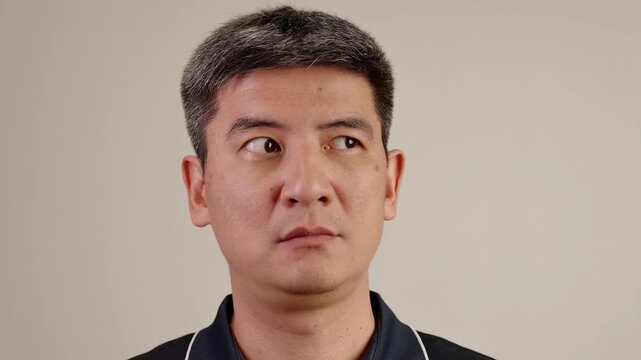 Mistrustful merchant in casual clothes moving his eyes side to side with cautious, uncertain expression, captured against neutral studio background.
