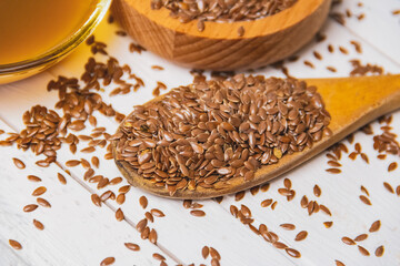 A pile of flax seeds and linseed oil on a wooden white table. Linen linen concept