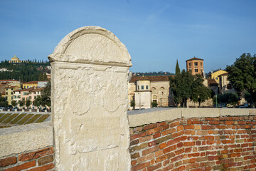 An ancient historical monument made of white stone on a red brick bridge in the city of Verona, Italy The sky is bright blue.