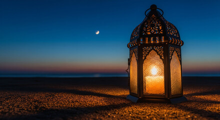 Traditional decorative lantern with candlelight standing on beach sand under a colorful evening sky with crescent moon.