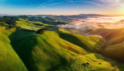 aerial view of lush green hills at sunrise with fog