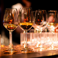 Elegant scene of wine being poured into glasses aligned in a row, showcasing the rich colors and graceful flow of the liquid, set against a dark, warm background, ideal sophisticated dining settings