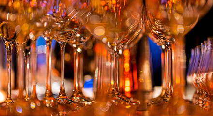 Elegant scene of wine being poured into glasses aligned in a row, showcasing the rich colors and graceful flow of the liquid, set against a dark, warm background, ideal sophisticated dining settings