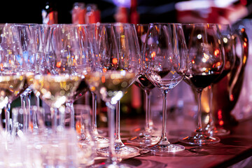 Elegant scene of wine being poured into glasses aligned in a row, showcasing the rich colors and graceful flow of the liquid, set against a dark, warm background, ideal sophisticated dining settings