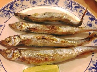 4 grilled whole fish with golden-charred skin arranged horizontally on vintage ish plate with lime