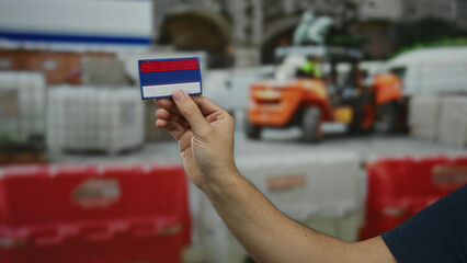 Man holds a patch resembling the russian flag at an outdoor construction site, highlighting cultural identity in a work environment.