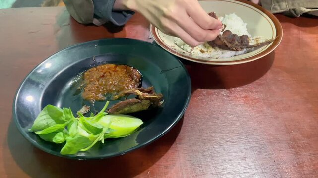 Eating pecel lele video with rice, sambal, and raw vegetables.