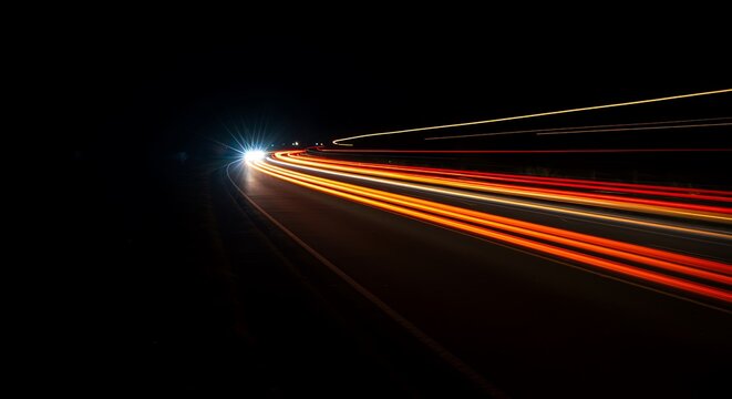 Streaks of light along a dark asphalt road at night
