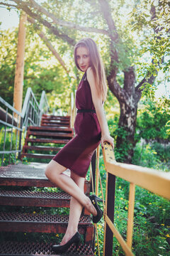 Elegant woman standing on outdoor metal stairs in summer park