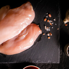 Fresh raw chicken breast fillet, organic meat. Black background. Top view