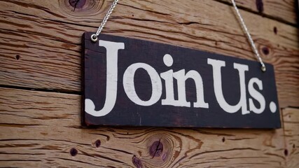 Close-up of rustic wooden hanging sign with white join us text on timber wall, recruitment and community invitation business concept for vacancy