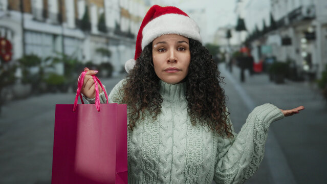 Woman outdoors wearing santa hat holding shopping bag on street during holiday season