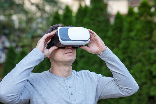 Middle-aged man wearing virtual reality headset outdoors, looking up and engaging with an immersive virtual experience
