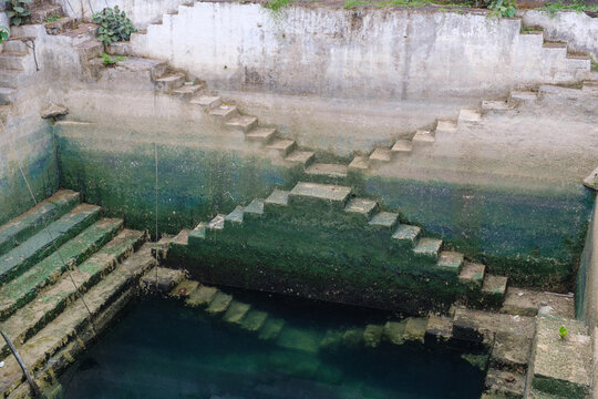 Ancient stepwell with geometric stone stairs descending into water, showcasing traditional rainwater harvesting and unique Indian architectural heritage