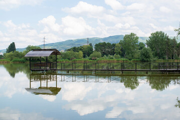 Obraz premium an iron teracce with a bridge stands on a lake in the mountains in summer and is reflected in the water