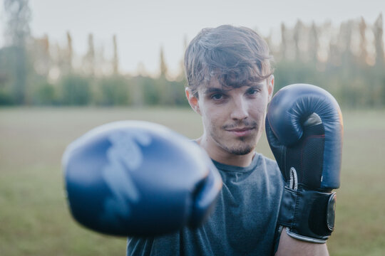 Boxer throwing punch with gloves towards camera in open air autumn park