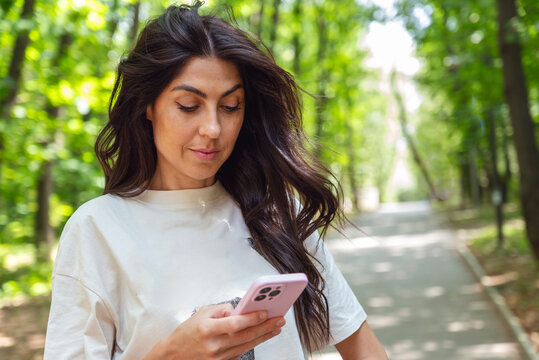 Beautiful Brunette Woman using her phone in the summer park