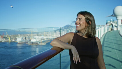 Fototapeta premium Woman points finger to sea from cruise ship deck, leaning on glass rail with bare arm and smiling; carefree joy.