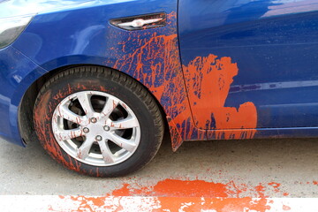 The blue passenger car was damaged by vandals with paint.	