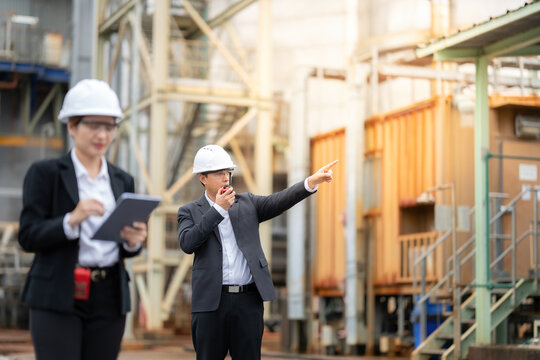 Using modern tools and safety equipment, Asian male and female engineers inspect power plant machinery and structures, reinforcing operational quality and reducing potential industrial risks.