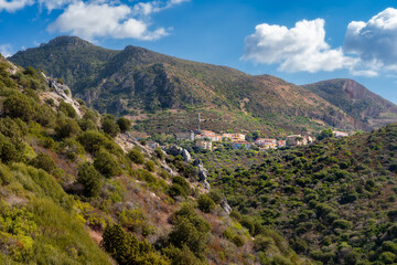 Fototapeta premium View of the Sardinian town of Nebida, nestled among the mountains. A sunny day on the hiking trail of Saint Barbara, the patron saint of miners.