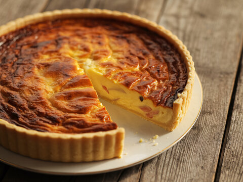 Indulge in a slice of freshly baked quiche lorraine, perfect for brunch or a cozy meal, showcasing rustic charm and culinary delight on a wooden table