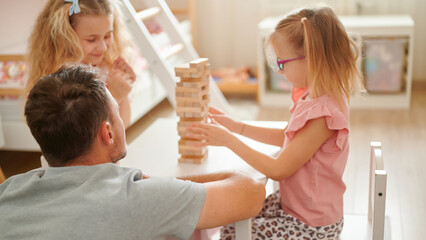 Children playing a wood block stacking game indoors