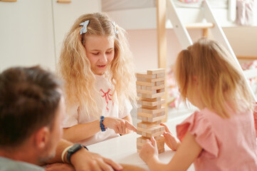 Kids playing wooden block stacking game indoors