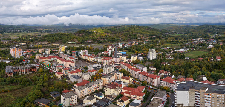 Panoramic aerial view of Rrëshen with residential blocks and autumn hills under dramatic cloud layers.
