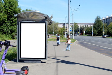 There is an empty advertising banner at a bus stop in the city.