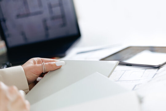 Female interior designer reviewing plans with tablet and laptop setup, selects colors of materials - Powered by Adobe