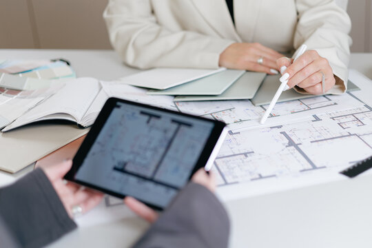 Architecture meeting: professionals reviewing building design plans of interior on digital tablet and paper for client