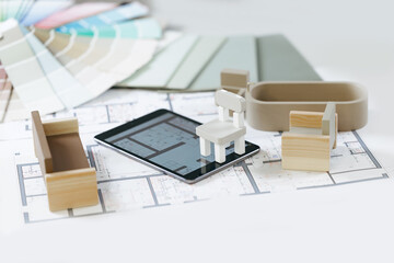 AI Digital designer assistant for apartment planning. Architectural online design with technology tablet and wooden miniatures on blueprints