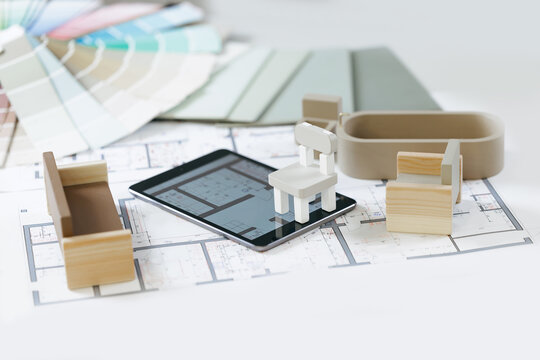 AI Digital designer assistant for apartment planning. Architectural online design with technology tablet and wooden miniatures on blueprints