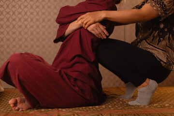 Traditional thai massage session with female therapist assisting young woman client